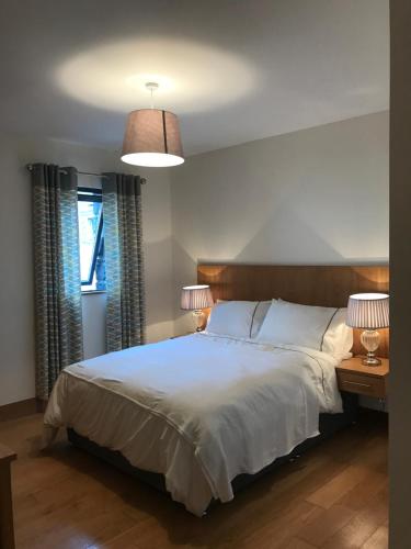 卡文Holiday Home On Farnham Estate的一间卧室配有一张带两盏灯的大型白色床。