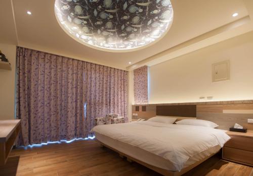 北竿马祖北竿舒漫活海景旅宿 的一间卧室配有一张大床和一个大型吊灯。