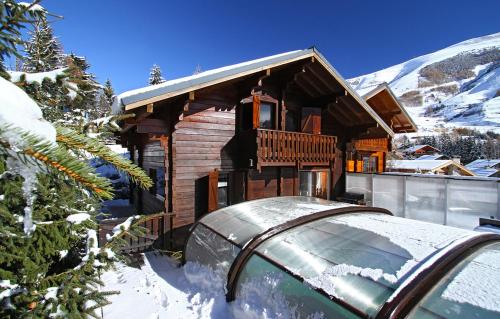 莱德萨阿尔卑斯Odalys Chalet Le Ponton的雪地里的小木屋,前面有车