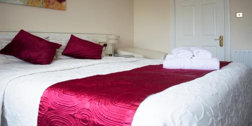 戈尔韦Balcony House的一张带红色枕头的白色床和毛巾