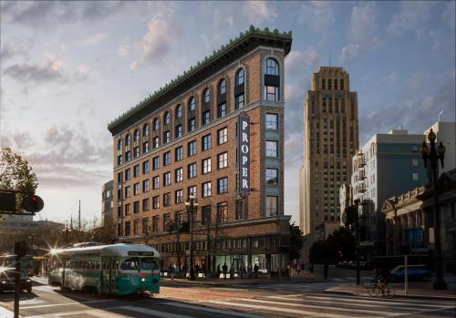 旧金山San Francisco Proper Hotel, a Member of Design Hotels的一辆绿色的巴士在建筑物前的街道上行驶