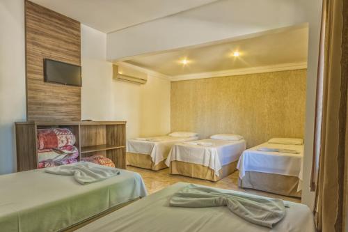 伊瓜苏Hotel Holiday Foz的酒店客房设有三张床和电视。