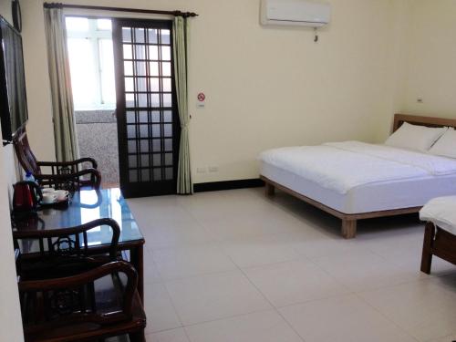 北竿罗马佳洲民宿的一间卧室配有一张床、一张桌子和一个窗户。