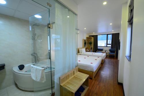 河内Blue Hanoi Inn Luxury Hotel的酒店客房配有一张床、淋浴和浴缸。