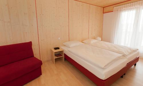 巴特温茨海姆Fewo-Kerschbaum的一间卧室配有一张床和一张红色的沙发