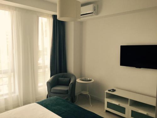 马马亚Mamaia Beach Side的酒店客房配有一张床、一把椅子和一台电视。