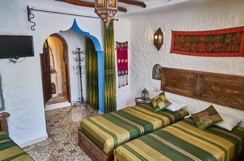 舍夫沙万达雅库摩洛哥传统庭院住宅的一间卧室设有两张床,墙上配有电视。
