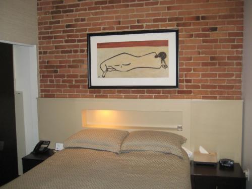 蒙特利尔乐瑞丽里昂酒店的一张床上方的图画砖墙