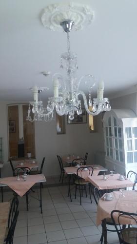 CorbenyLogis Hotel du Chemin des Dames的一间带桌椅和吊灯的用餐室
