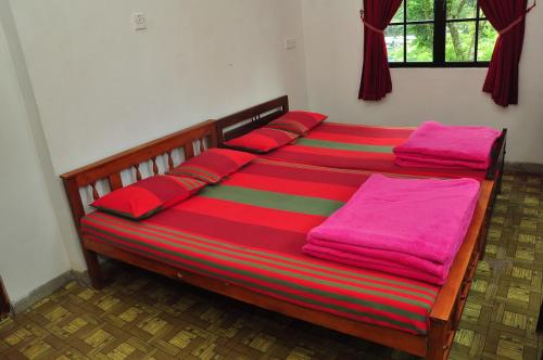 努沃勒埃利耶Akiko Rest的一张带红色枕头的床和粉红色的毯子