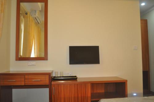 EttumānūrVettoor Nanas Inn的一间设有木桌的墙上电视的房间