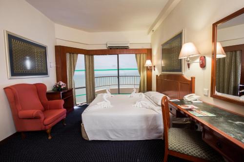 乔治市天堂沙滩度假村的酒店客房配有一张床、一张桌子和一把椅子。
