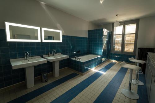 米尔库尔Les Gites Historiques的蓝色瓷砖浴室设有2个水槽和1个浴缸