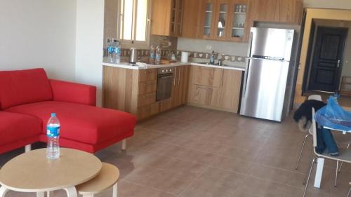 艾因苏赫纳Twin House in Telal的厨房配有红色的沙发、桌子和冰箱