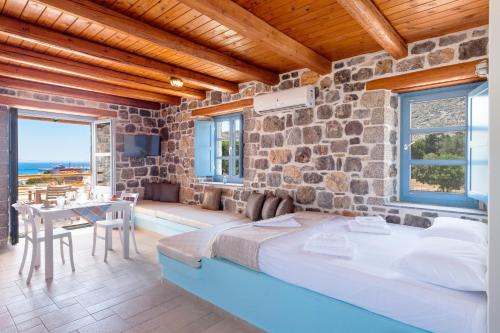 PsérimosPserimos Villas的带石墙的客房配有一张床和一张桌子。