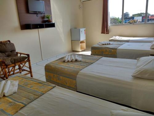 伊瓜苏阿尔沃拉达伊瓜苏酒店的客房设有三张床、椅子和电视。