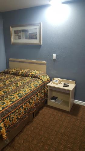 沙伦维尔旅游酒店的一间酒店客房,配有一张床铺和一张桌子上的电话