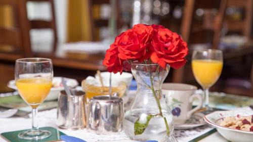 菲什加德Priskilly Forest Country House的一张桌子,上面有花瓶,上面有红花