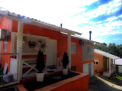 格拉玛多Glamour Gramado Residence的前面有两株盆栽植物的红色房子