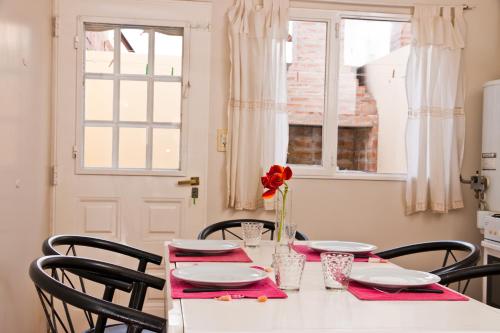 玛德琳港Complejo La Lucila的花瓶里带椅子的白色桌子和红花