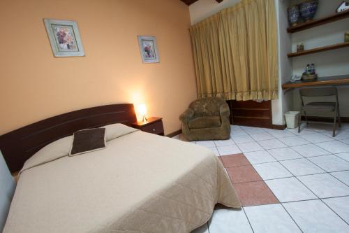 危地马拉康福特旅舍的一间卧室配有一张床、一把椅子和一张书桌