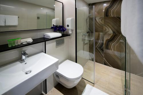 新加坡Hotel Mi Bencoolen的浴室配有卫生间、盥洗盆和淋浴。