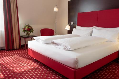 韦尔斯Best Western Plaza Hotel Wels的配有红色床头板的酒店客房内的两张床