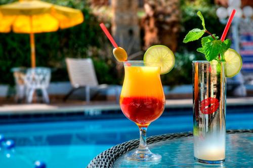 拉斯维加斯Shalimar Hotel of Las Vegas的坐在泳池旁的桌子上,喝上两杯鸡尾酒