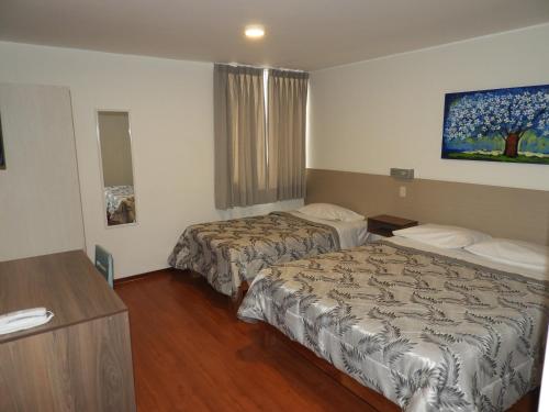 塔克纳Nice Inn Tacna的酒店客房设有两张床和一张桌子。