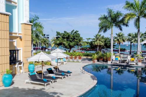 芭堤雅市中心Wave Hotel Pattaya的度假酒店的游泳池配有椅子和遮阳伞