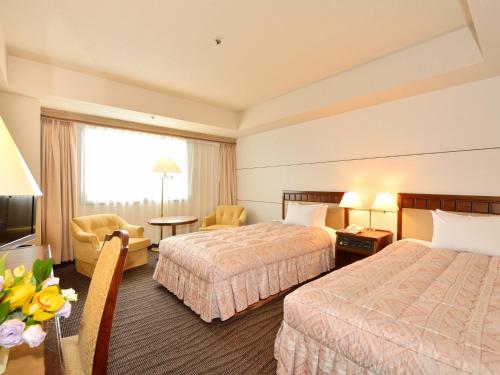 滨松滨松格兰饭店的酒店客房,设有两张床和一张鲜花桌。