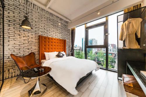 首尔天玺开浦酒店的卧室配有白色的床和砖墙
