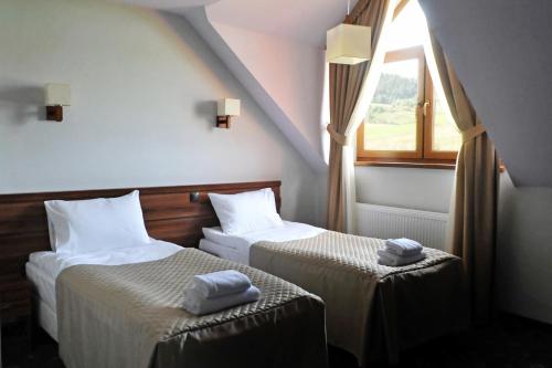 下乌斯奇基Zajazd Bieszczadzka Ostoja的带窗户的客房内的两张床