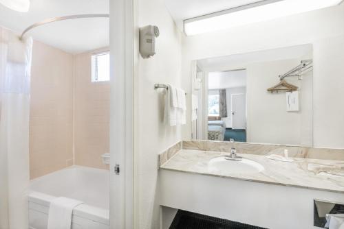 德明Days Inn by Wyndham Deming的一间带水槽、浴缸和镜子的浴室