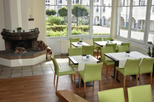GillenfeldLandhotel Gillenfelder Hof的一间带桌椅和壁炉的餐厅