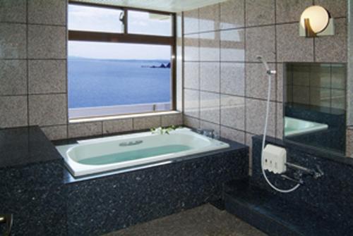 志布志市斯步赛瓦达凯库度假酒店的带浴缸的浴室和窗户。
