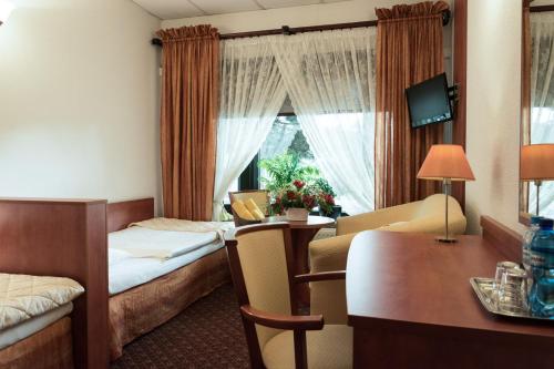 波兹南Hotel Astra Tajemniczy Ogród的酒店客房带两张床、书桌以及一间客房。