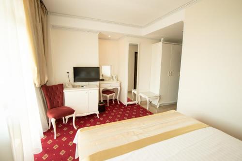 曼加利亚MSR Port Hotel的酒店客房配有一张床、一张书桌和一台电视。
