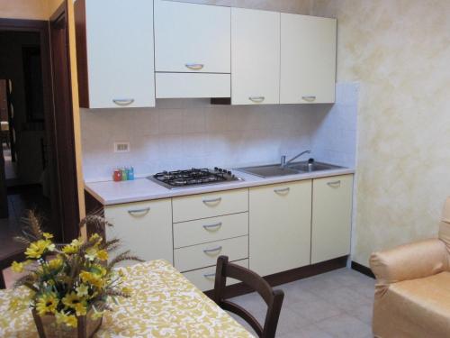 Notaresco圣玛利亚特努塔农家乐的厨房配有白色橱柜、水槽和桌子