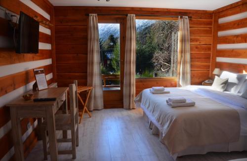 拉安戈斯图拉镇Casa del Lago Villa La Angostura的一间卧室配有一张床、一张书桌和一个窗户。