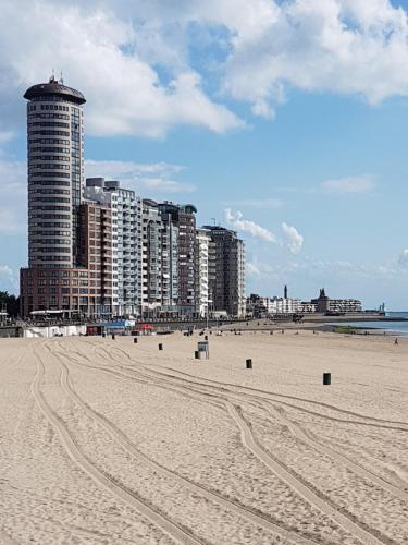 弗利辛恩Stad & Strandhotel Elisabeth的沙滩上高耸的建筑和沙滩上的足迹