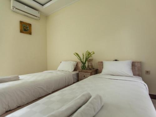 沙努尔乌玛巴古斯旅馆的配有白色床单的客房内的两张床