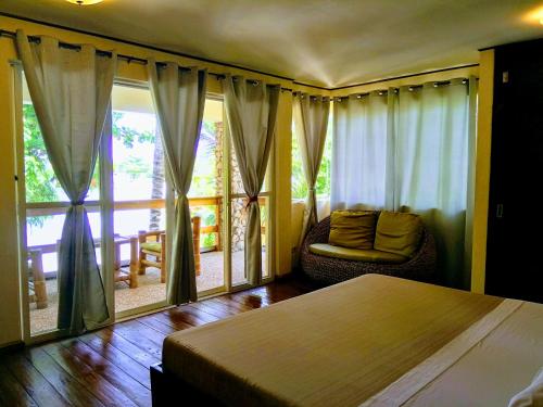 马拉帕斯加Angelina Beach Resort & Italian Restaurant Malapascua的卧室配有床、椅子和窗户。