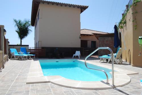 坎德拉里亚Villa El Tagoro的一个带蓝色椅子的庭院内的游泳池