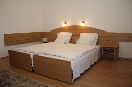 Gyömrő猫头鹰酒店的一间卧室配有一张大床和木制床头板