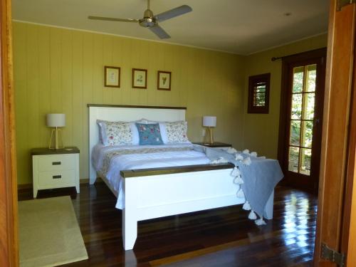 Cooroy木兰度假屋的卧室配有白色的床和2个床头柜