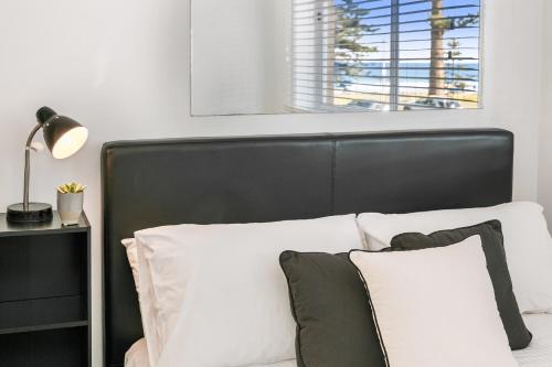 悉尼黄金英里海滨公寓的一张带黑色床头板和白色枕头的床