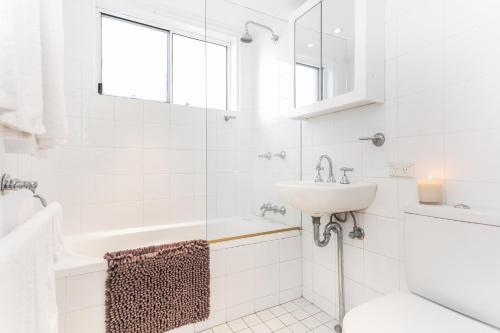 悉尼黄金英里海滨公寓的白色的浴室设有水槽和浴缸。