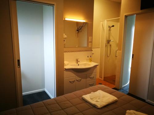 基督城白桦树机场汽车旅馆的一间带床、水槽和淋浴的浴室