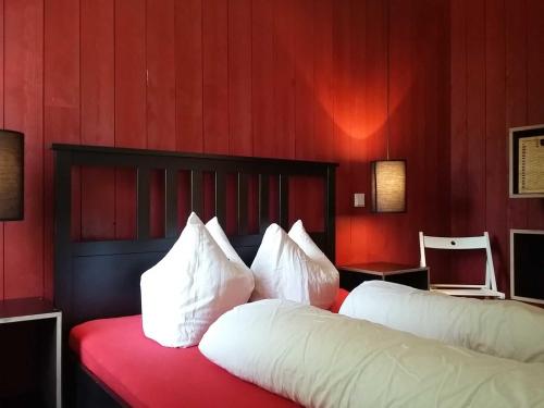 Klein StrömkendorfRotes Strandhaus mit Boot am Salzhaff, 50m zum Strand的一间卧室配有两张带红色墙壁和白色枕头的床。